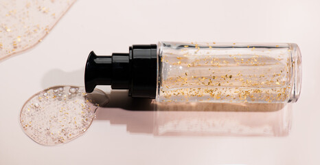 Fluid cosmetic product 24k gold gel in a glass bottle on beige background. Beauty serum, peptides, essence, wellness ads, cosmetic presentations. Skin care, face cream, mask, body lotion, moisturizer.