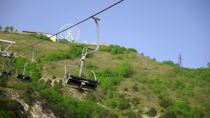 Empty Chairlift Seats Against Ferris Wheel On Ridge, WideAngle Hillside Panorama With Vacant Chairs Swaying