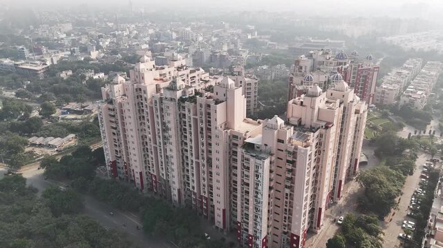 Aerial view of Jaypee Greens, showcasing high-rise residential towers surrounded by tree-lined roads and dense greenery under light NCR haze.