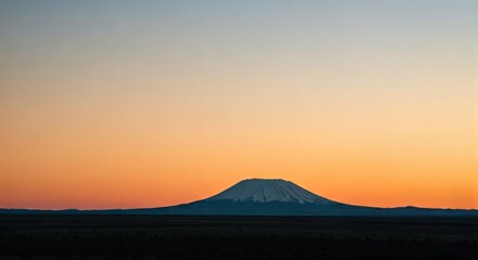 A symmetrical, snow-capped mountain silhouette against a vibrant, gradient sunset sky