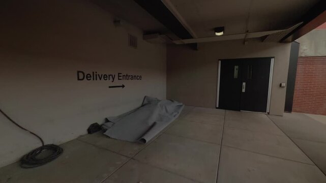 Steady forward pan toward delivery entrance doors in quiet urban service corridor