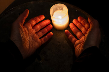 Hands and a candle in a Catholic church.