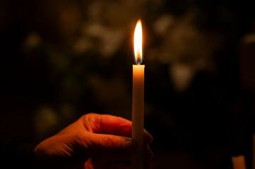 Hands and a candle in a Catholic church.