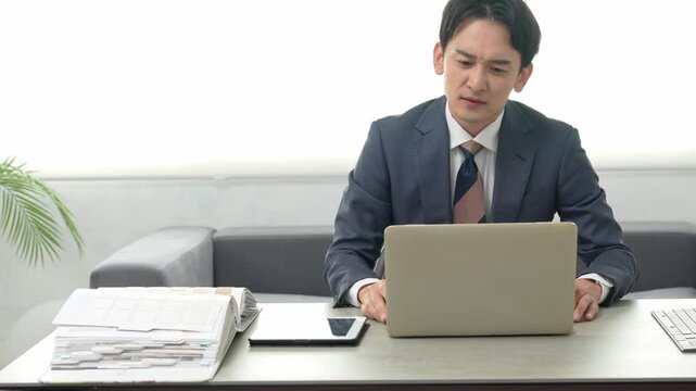 パソコン仕事をしながら悩む男性