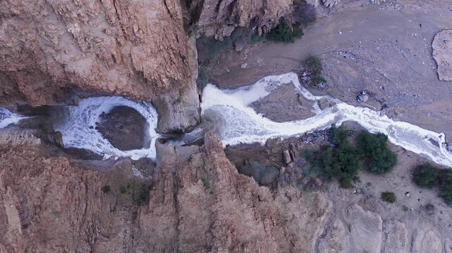 Top down aerial drone view of the Kidron River flowing with muddy flash flood water around a unique horseshoe bend in the deep Judean Desert canyon, Israel.