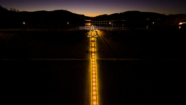 Cinematic drone photo along the illuminated Himmelstreppe stairs in Meschede at sunset. 333 steps leading to the Hennesee dam wall.