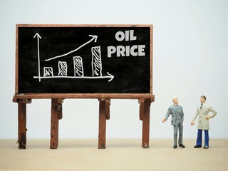 Mini toy of action figure at table with blurred background. Business financial photography concept design. Minifigure of businessman character with OIL PRICE graph at blackboard. Increase arrow chart.