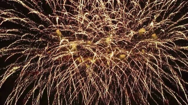 Aerial drone view of fireworks exploding over a city park at night, colorful sparkles bursting in the sky, high altitude wide shot, festive celebration atmosphere, cinematic night scene, 15 August 202