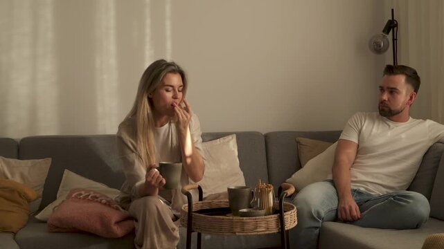 Couple Enjoying Snacks and Conversation on Sofa at Home