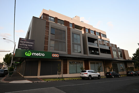 Apartment building with ground floor Woolworths Metro supermarket, with Gary Peer real estate sign promoting apartments selling now