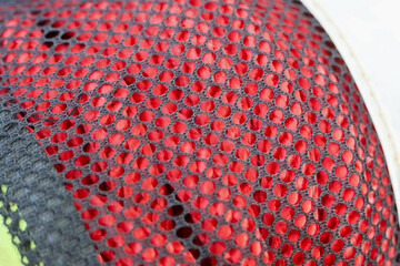 Close up texture of red synthetic mesh fabric on sport shoe displaying intricate perforated pattern and vibrant sporty style conveying dynamic energy and high performance design potential