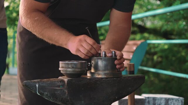 Caucasian Blacksmith Hands Arranging Metal Molds On Anvil Outdoor Studio, Careful Assembly With Hammer
