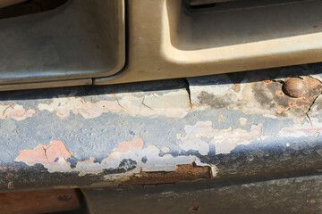 Closeup detail of rusty car bumper showing severe corrosion and peeling paint texture neglected old vehicle grill surface with worn metal automotive bodywork abstract damage and distressed grunge