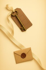 Antique Brass Key with Ribbon and Sealed Envelope on Warm Yellow Background