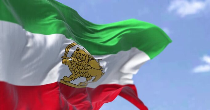 Iran Pahlavi-era Lion and Sun flag waving against blue sky