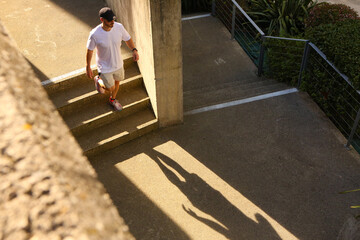 A young man in sportswear, walking down some stairs in the city