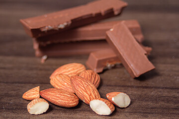 Almonds and chocolate rest on a wooden floor, creating a warm and natural food-themed still-life scene.