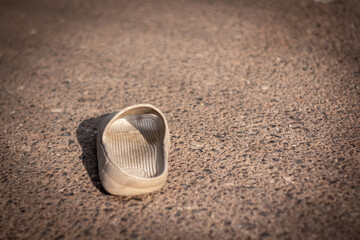 Single shoe abandoned on concrete symbolizing loss, loneliness, and separation.