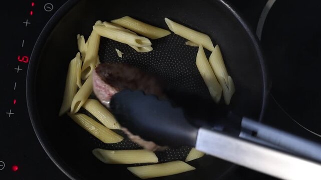 Cuisson d'un steak hach&eacute; dans une po&ecirc;le sur une plaque de cuisson en c&eacute;ramique.
