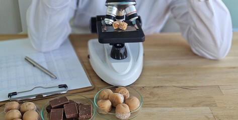 Researcher examines chocolate samples using microscope and notes