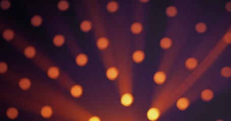 Warm yellow light shines through round holes in a black background