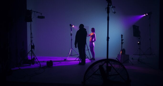The photographer takes off the model's hand behind the glass. Working as a photographer and model in a studio