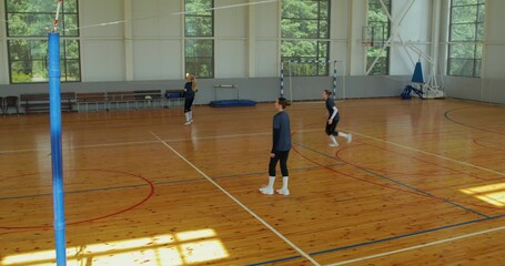 Top view of the girls actively serving, hitting, and passing the ball to each other during the game.