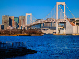 Obraz premium Rainbow Bridge by Daiba Park and Odaiba Seaside Park in Minato City, Tokyo, Japan, a calm waterfront scene blending architecture and coastal beauty.