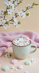 Hot chocolate with pastel marshmallows and blooming branches on table  