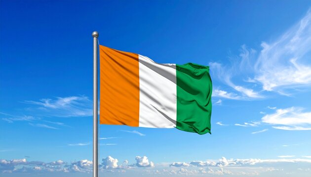Irish flag waving on flagpole against bright blue sky with clouds, national tricolor symbol