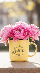 Pink peonies in yellow mug labeled June on outdoor table  