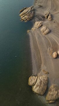 Rocky lakeshore and green lake water with bird flying, Almendra Reservoir, Spain