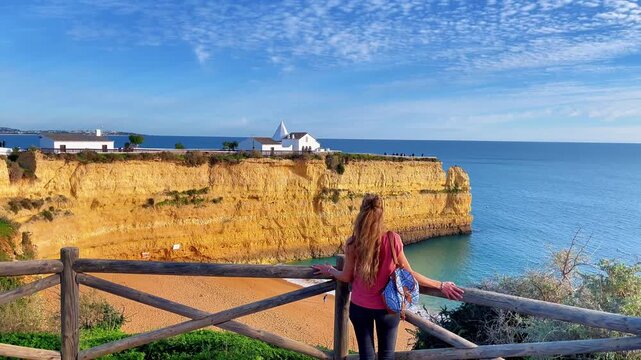 Woman tourist looking at spectacular cliffs on chapel of Senhora da Rocha. Algarve, Lagoa, Arma&ccedil;&atilde;o de P&ecirc;ra