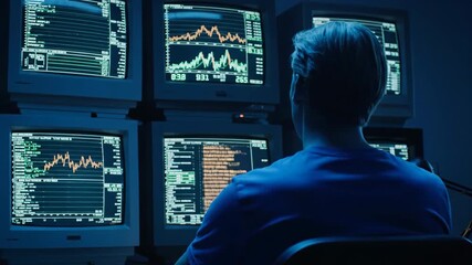 Man watches multiple computer monitors showing stock market data and charts in a dimly lit room. - Powered by Adobe