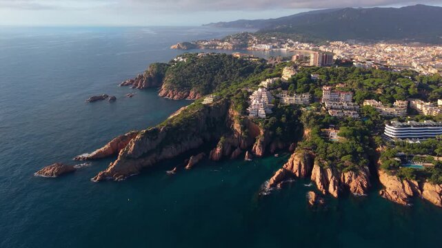 Stunning aerial perspective showing the rocky coastline and beautiful seaside town of sant feliu de guixols, with the s'agaro bay and beach in the background on the sunny costa brava