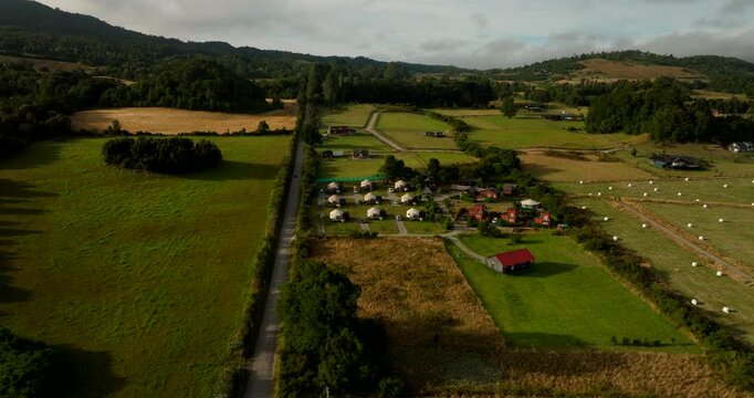Freen farmland and volcanic landscape with eco tourism huts near Puerto Varas and Osorno in Chile, aerial dolly