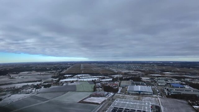 An immersive pilot&rsquo;s perspective in the final approach to Munich airport runway (MUC) RWY26L, taken from a jet cockpit, with a winter snowed lanscape under a clouded sky.