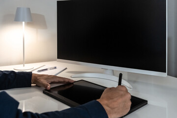 Creative professional using a graphics tablet and stylus, ready for digital design work on a blank monitor.