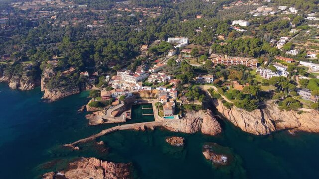 Stunning aerial perspective showing the picturesque coastal village of platja de fornells, nestled between rocky cliffs and clear turquoise waters on spain's beautiful costa brava