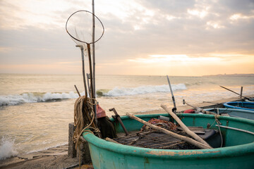 Traditional fishing boat with nets on sea shore at sunset