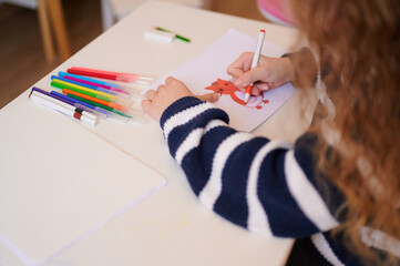 Child drawing picture with markers on table