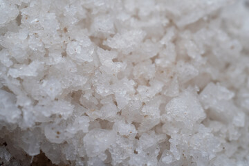 Close up shot of coarse white sea salt grains. Detailed crystalline texture of organic mineral for culinary, spa, and health concepts.