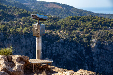 Panoramic binoculars on a cliff top overlooking the Butterfly Valley and the Mediterranean sea. Scenic viewpoint in Faralya near Oludeniz with a view of the deep canyon and mountains.  Turkey