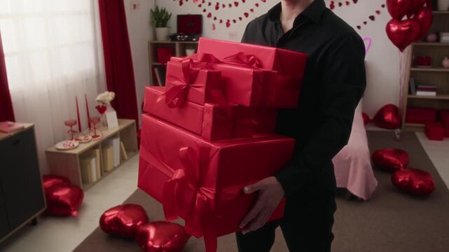 Midsection view of unrecognisable man wearing black outfit holding stack of gift boxes in festive room decorated for Valentines day celebration