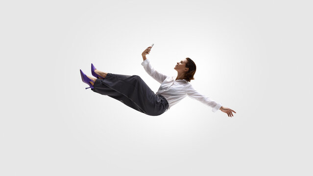 Business woman levitating and taking selfie on smartphone. Concept of personal branding, social media management, confident self presentation, online presence and modern professional communication.
