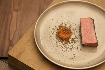 Healthy, high-protein gourmet meal featuring a lean slice of grass-fed beef steak paired with a nutrient-rich cured egg yolk and shaved truffle on a minimalist, earth-toned ceramic plate.