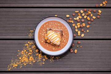 Healthy eating inspired dessert featuring a rich flourless dark chocolate brownie topped with a light yogurt quenelle, salted caramel drizzle, and antioxidant-rich peanuts for a balanced treat.