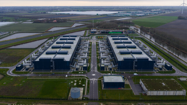 Aerial view of the vast Agriport data center complex, a stark contrast against the surrounding flat landscape and waterways, Middenmeer, Netherlands.