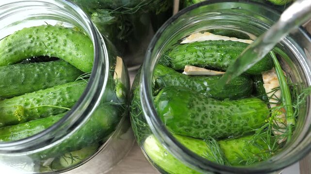 Sour cucumbers, preserves for winter.  Woman is pouring salt water into the jar with cucumbers. 