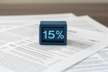 15 percent blue digital cube floating above printed financial documents, symbolizing interest rate, tax, or discount, with modern and professional atmosphere for business or finance concepts